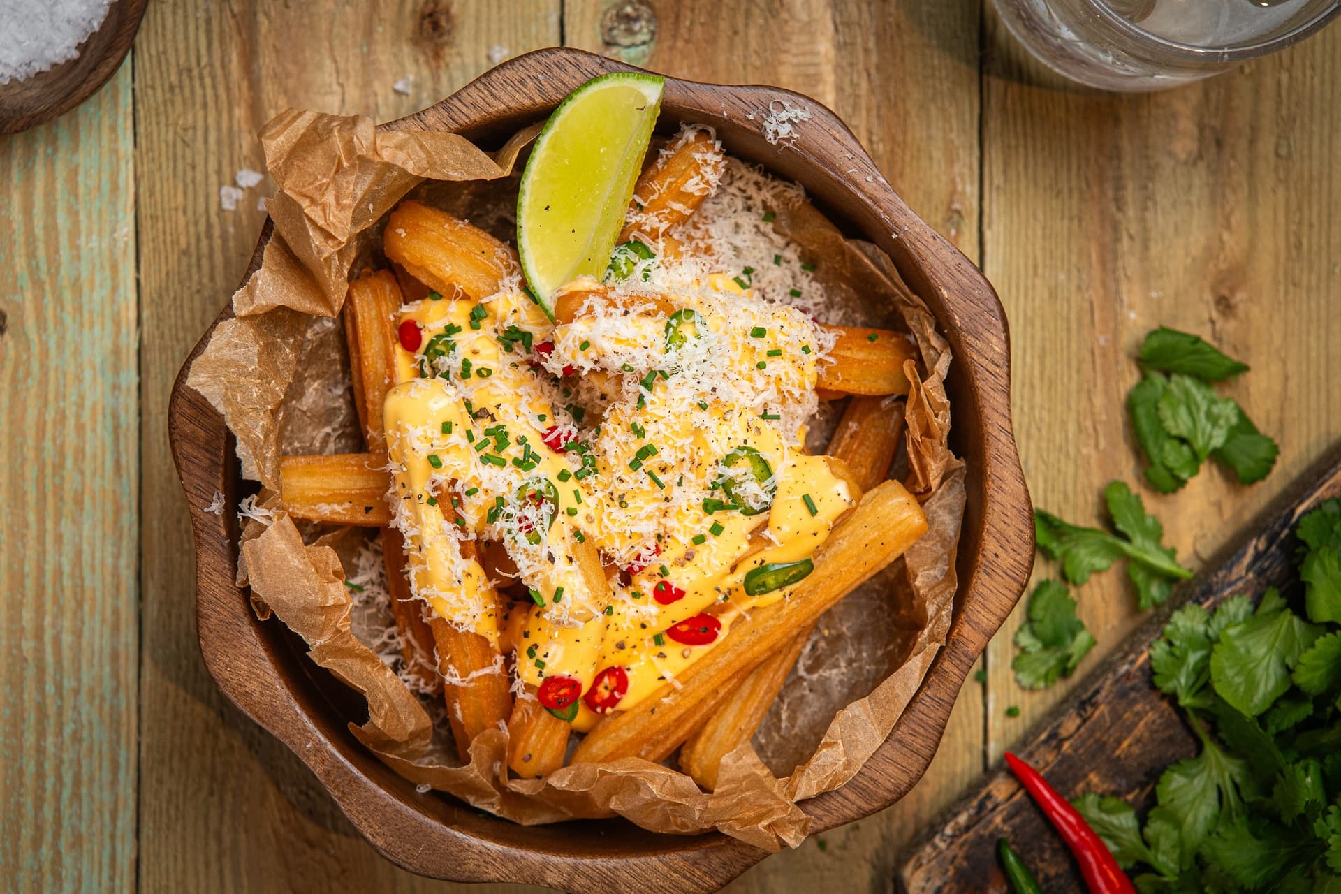 churros Aviko podane w restauracji w wersji loaded, z sosem serowym, papryczką chili, posypane tartym serem i udekorowane ćwiartką limonki