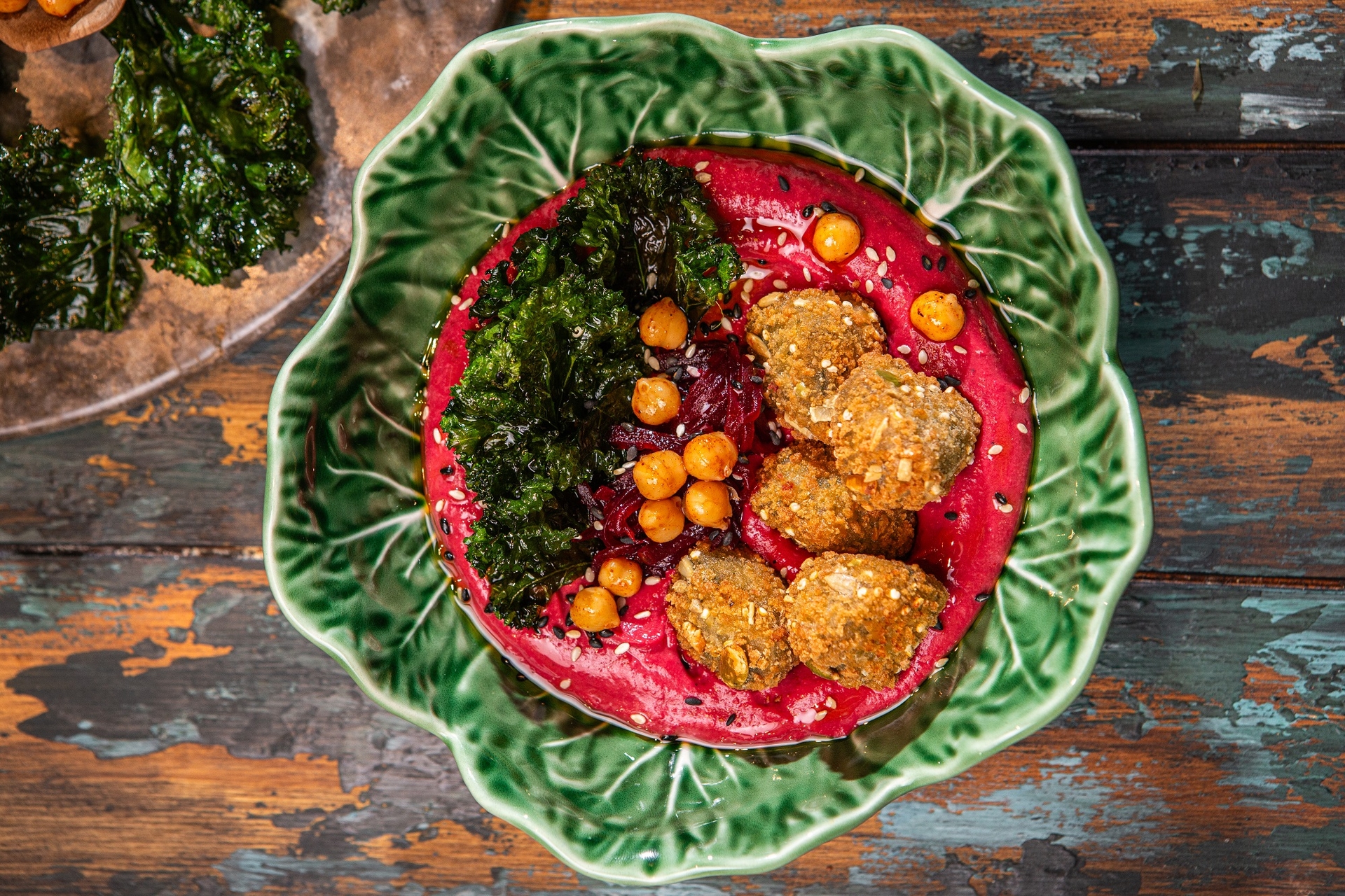 humus z buraka podany w miseczce w restauracji, z chipsami z jarmużu, pieczoną ciecierzycą i przekąskami falafel Aviko