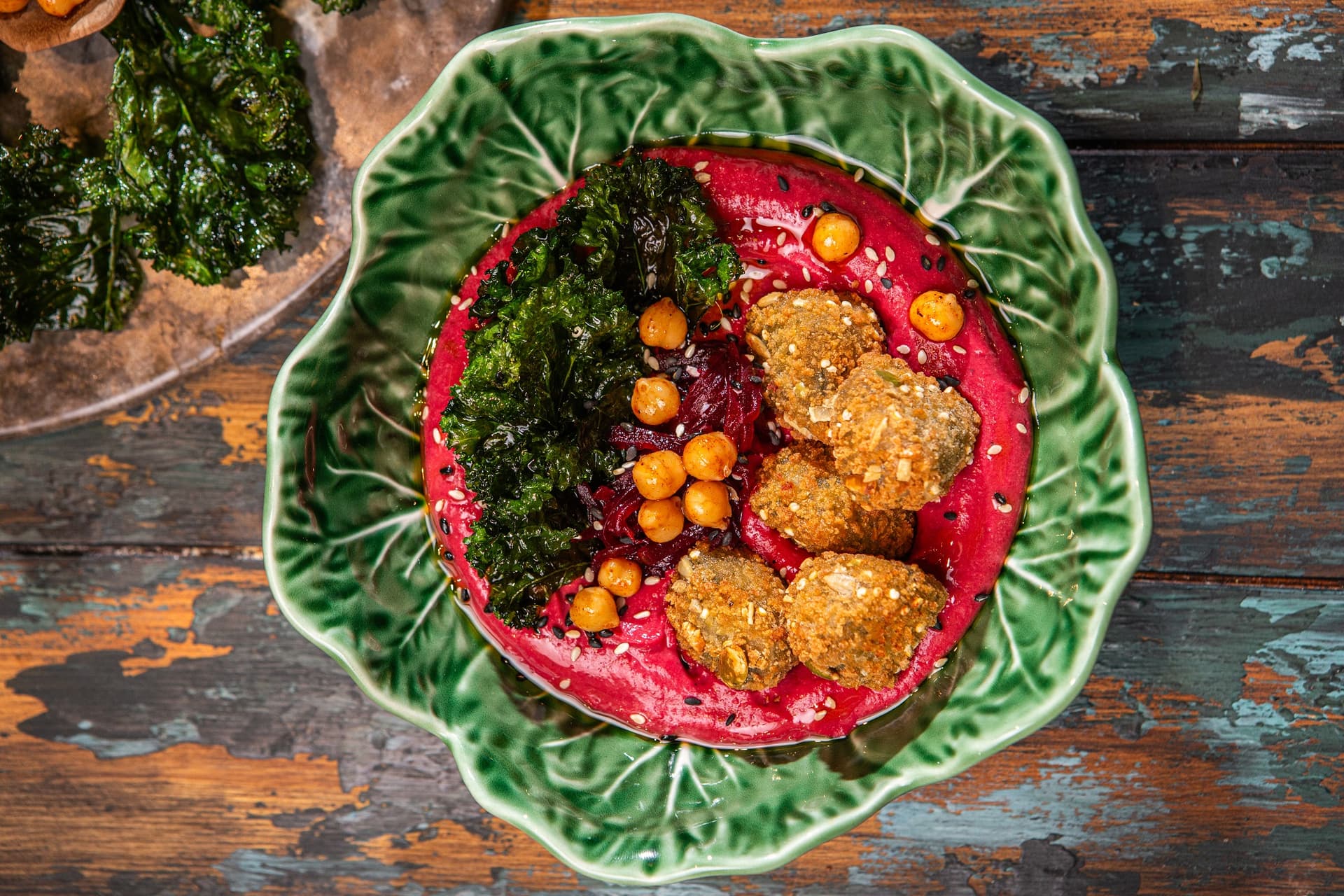 humus z buraka podany w miseczce w restauracji, z chipsami z jarmużu, pieczoną ciecierzycą i przekąskami falafel Aviko