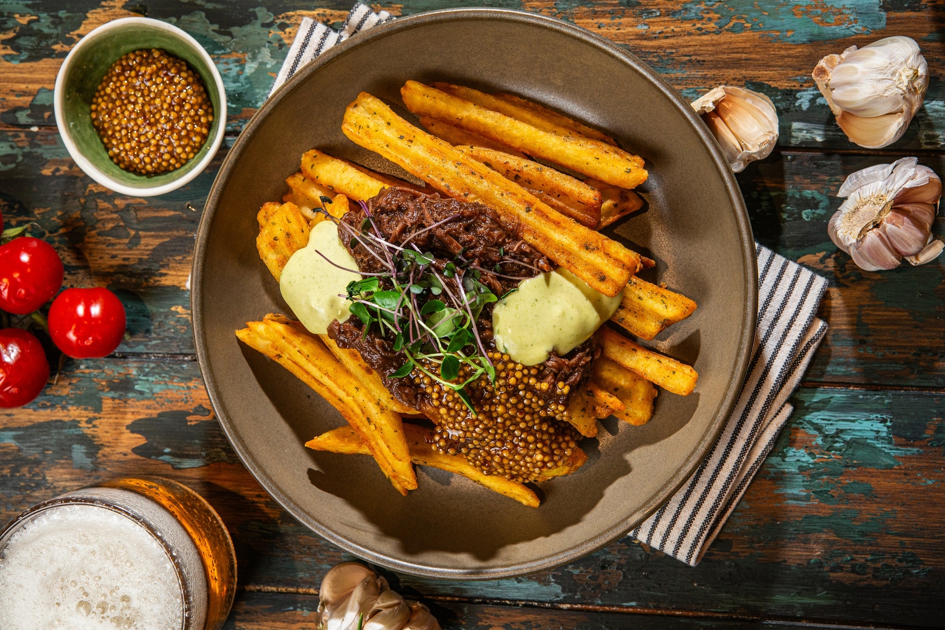 Gulasz wołowy podany w restauracji z karbowanymi frytkami z dodatkiem ziół, musztardą francuską i sosem